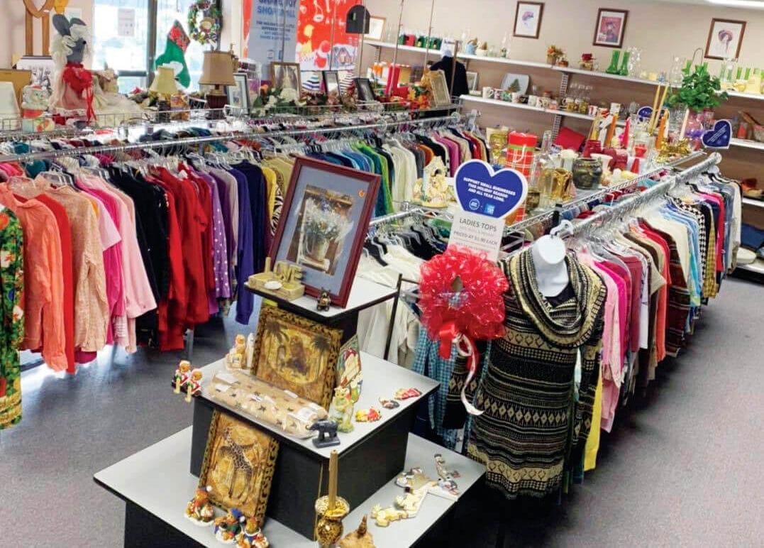 Inside Mountain Treasures Thrift Store featuring isles of women's tops and shelves of home décor items.