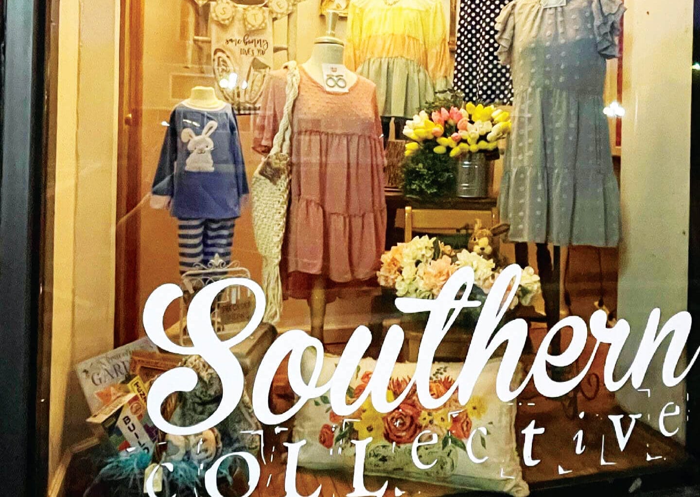 The front window of Southern Collective in Gate City with clothing and floral arrangements on display.