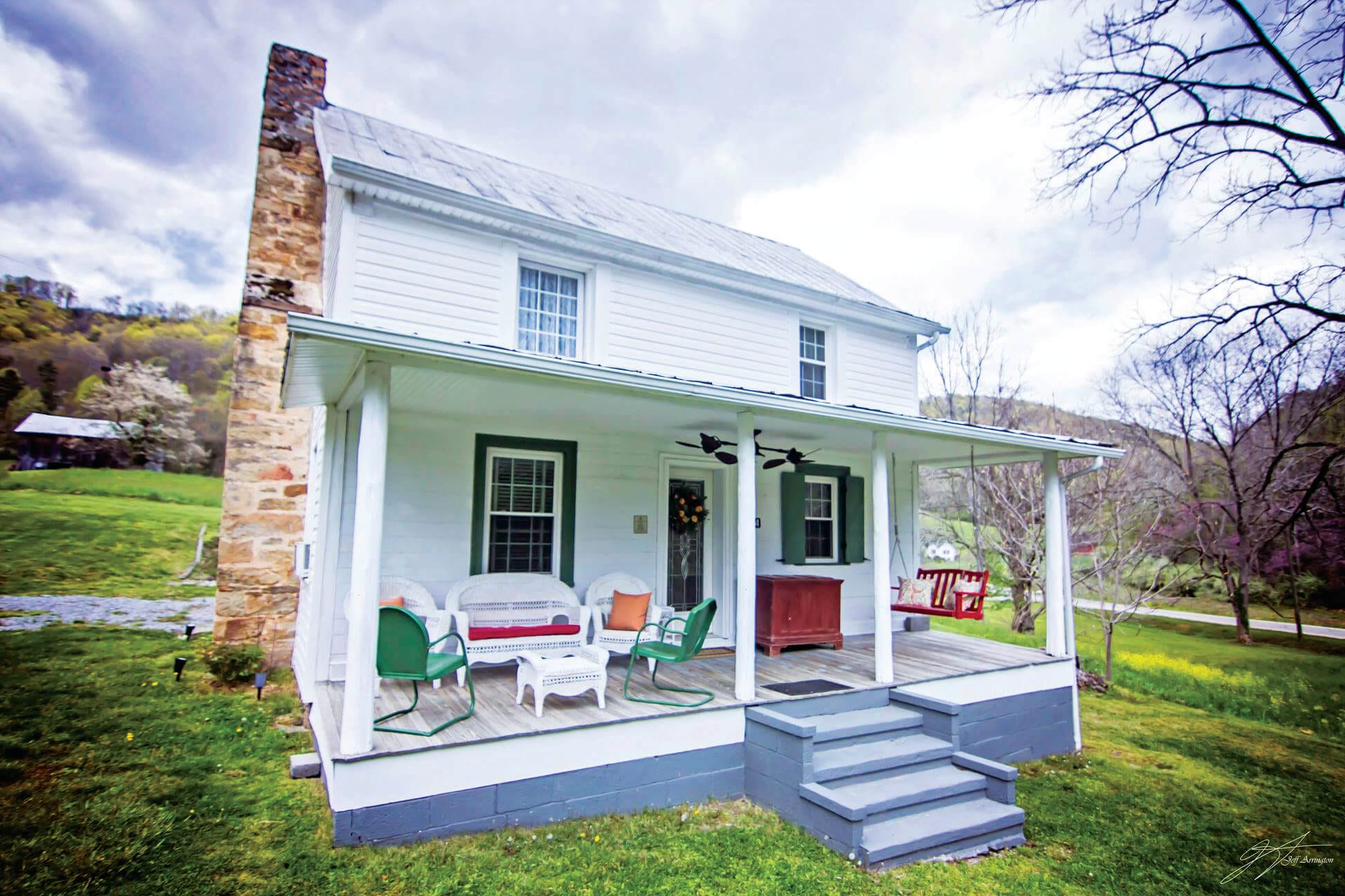 The outside of the Fulkerson-Hilton House showcases a front porch with wicker patio furniture and a porch swing.