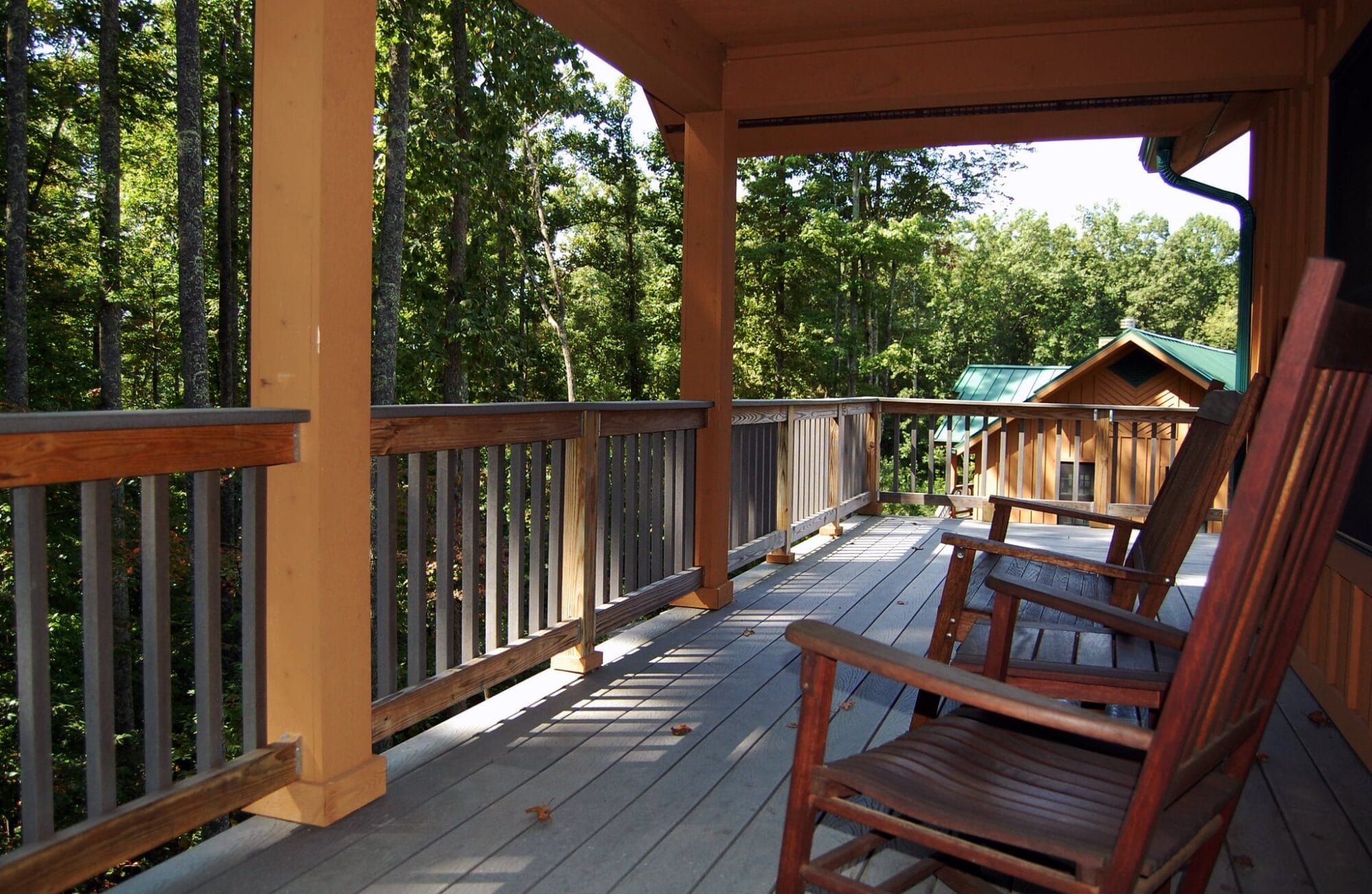 The front porch of one of the cabins at Natural Tunnel State Park includes two rocking chairs and a small table.